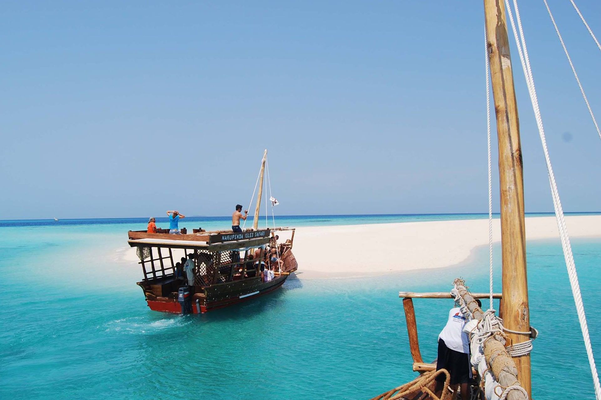 Traditional dhow moored at a white sandbank in turquoise water off Zanzibar