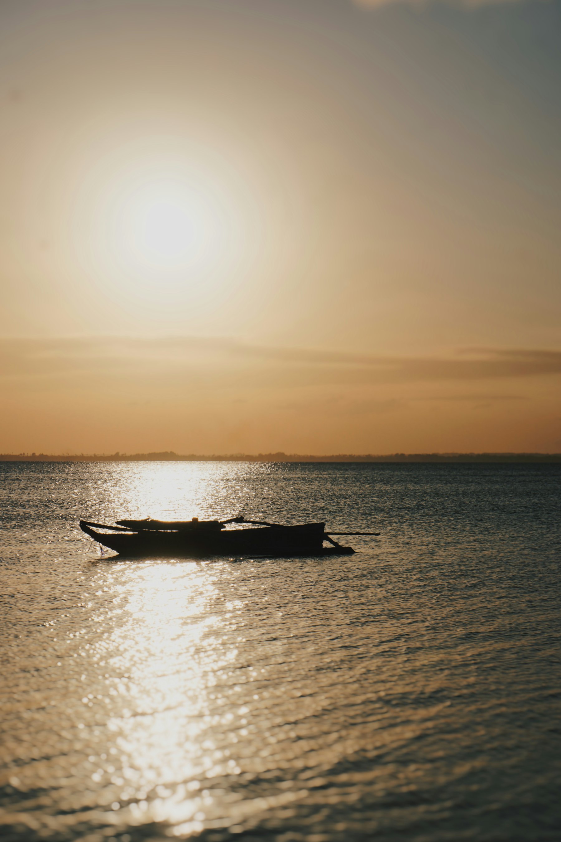 A dhow silhouetted against the sunset over the sea in Zanzibar